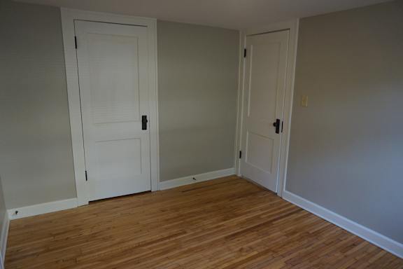 A room with two white doors and wooden floors.