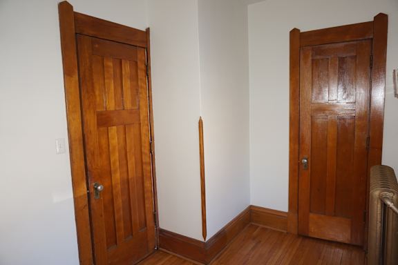 A room with two wooden doors and a white wall.