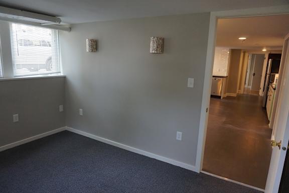 A room with a carpeted floor and a window with blinds.