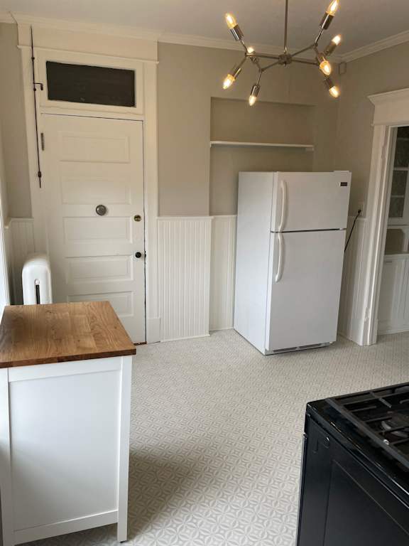 A kitchen with a white fridge and a black oven.