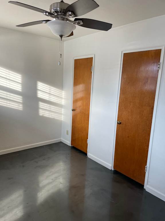 A room with a ceiling fan and two doors.