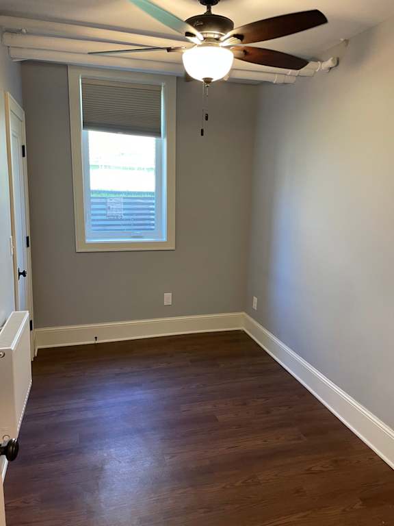 A room with a ceiling fan and a window with blinds.
