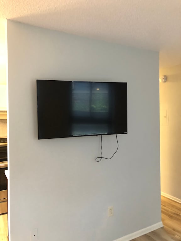 A black television is mounted on a white wall.