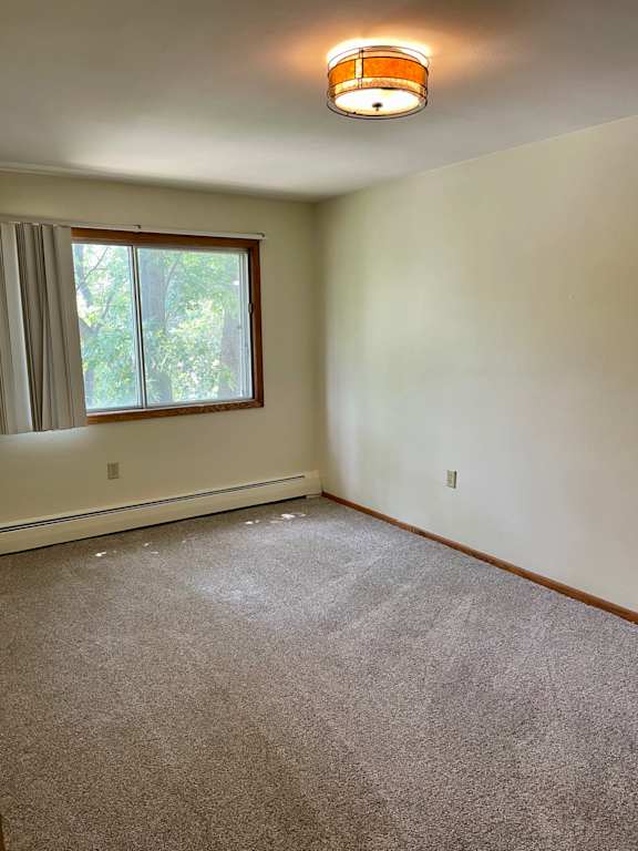 A room with a carpeted floor and a window with curtains.