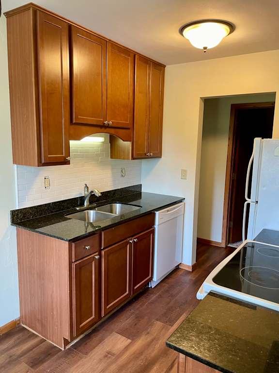 A kitchen with wooden cabinets and a black counter top.
