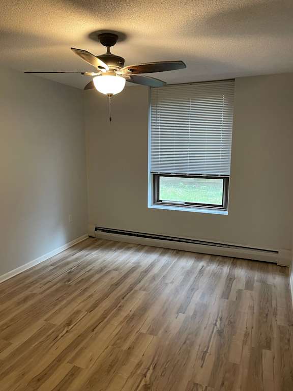 A room with a ceiling fan and a window with blinds.