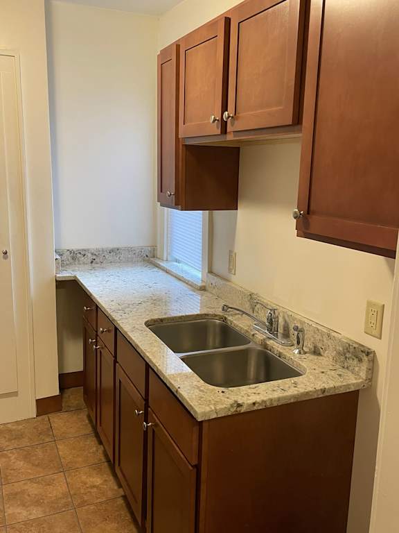 A kitchen with brown cabinets and a marble countertop.
