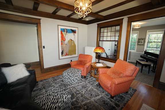 A living room with a black and white rug and orange chairs.