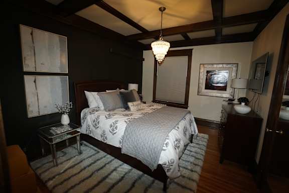 A bedroom with a large bed and a chandelier hanging from the ceiling.