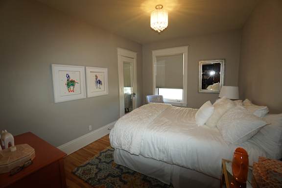 A bedroom with a bed, nightstand, and two pictures on the wall.