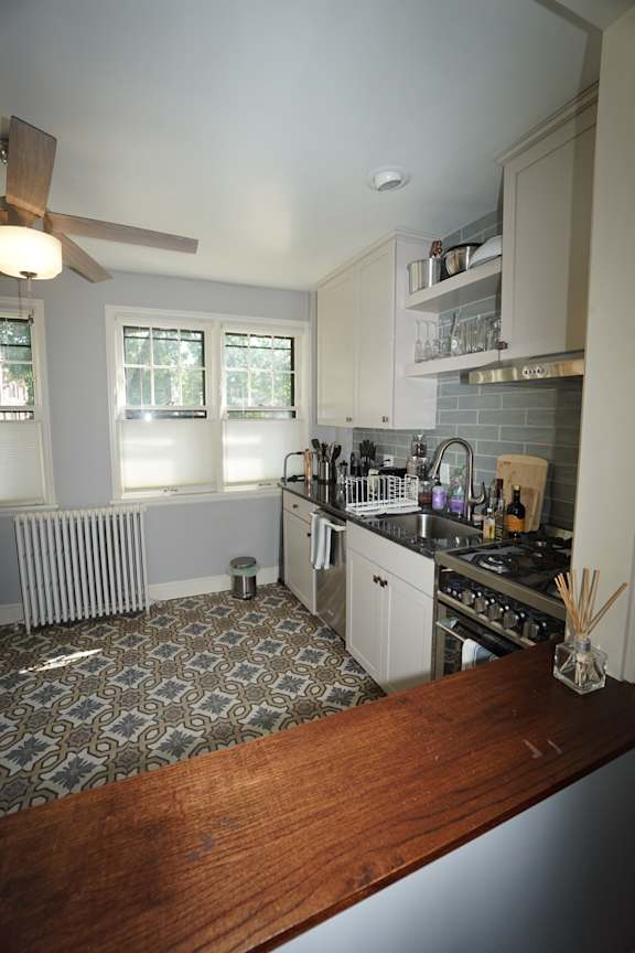 A kitchen with a wooden counter top and a tile floor.