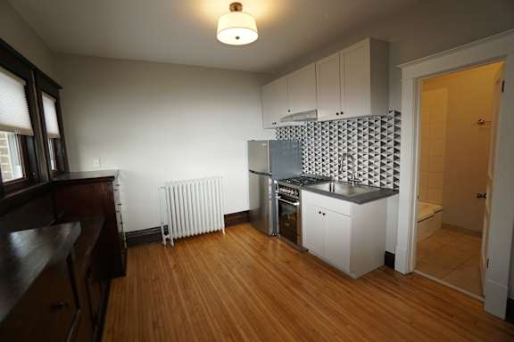 A kitchen with white cabinets and a wooden floor.