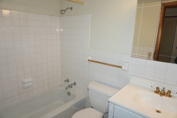 A white bathroom with a tub, toilet and sink.