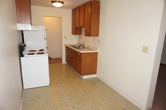 A kitchen with a white refrigerator and brown cabinets.