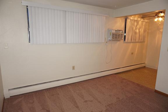 A room with a carpeted floor and a window with blinds.