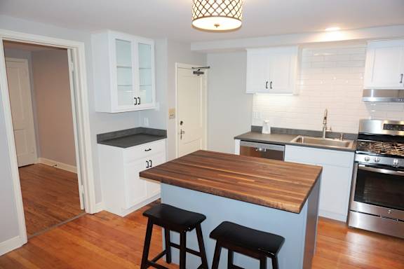 A kitchen with a wooden counter top and bar stools.