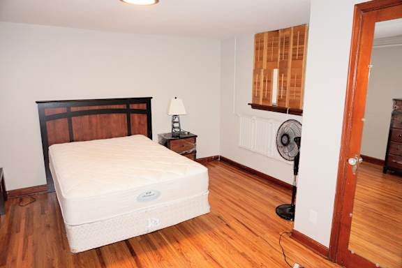 A white mattress is on a wooden floor in a room.