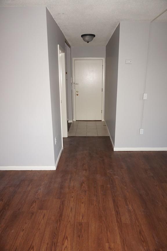 A hallway with a white door and brown floors.