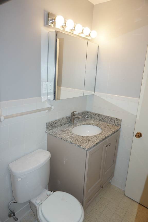 A bathroom with a toilet, sink, and mirror.