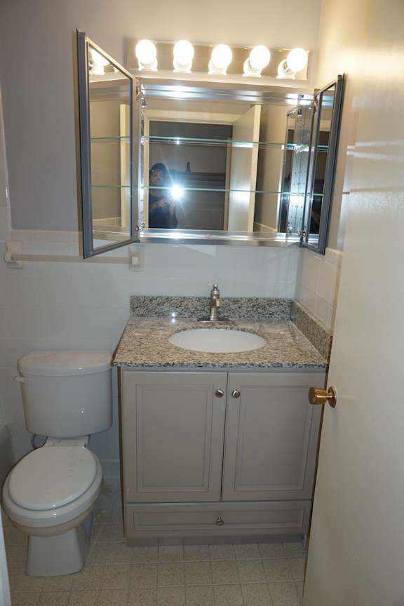 A bathroom with a toilet, sink and mirror.