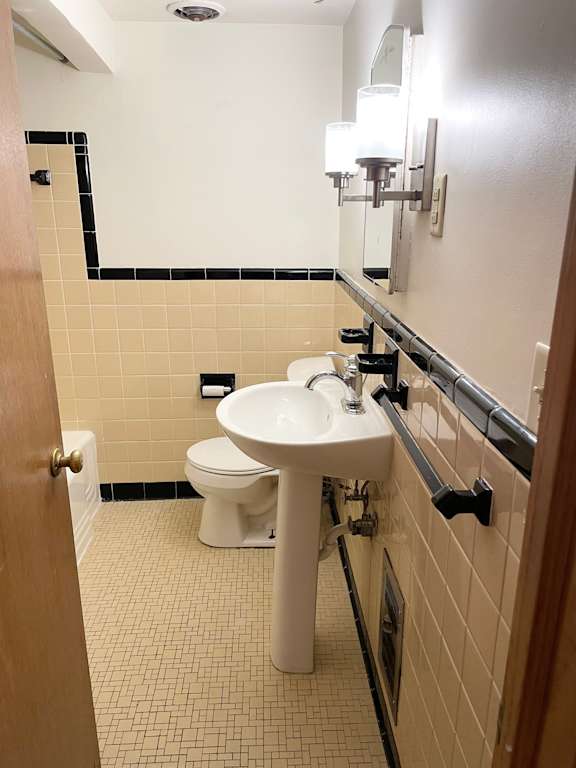 A bathroom with a sink, toilet and mirror.