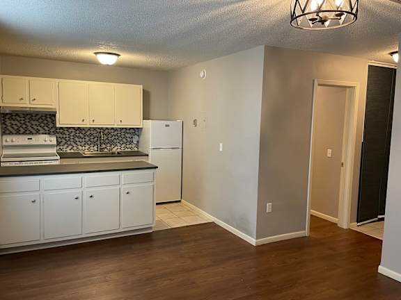 A kitchen with white cabinets and a black and white backsplash.