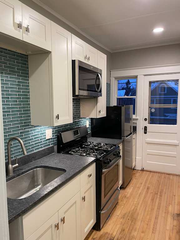 A kitchen with black appliances and white cabinets.