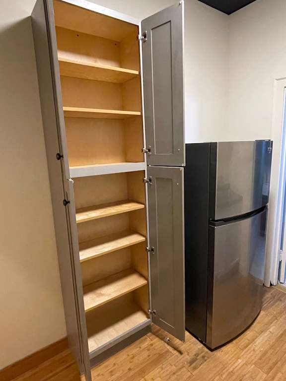 A kitchen with a black fridge and a white door cabinet with shelves.