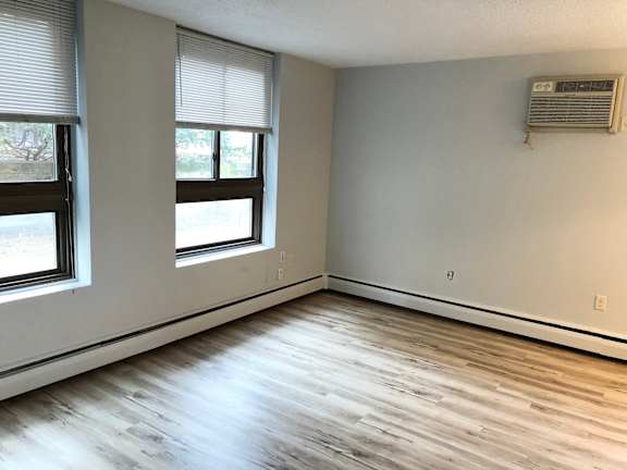 A room with a window and a wall-mounted air conditioner.
