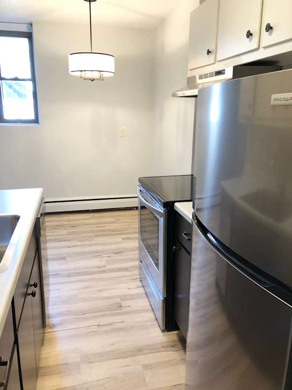 A kitchen with a stainless steel refrigerator and wooden floors.