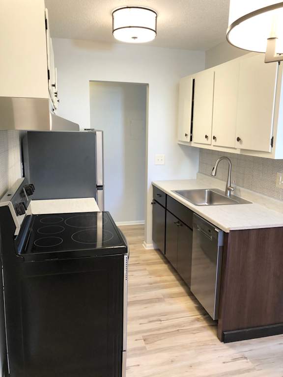 A black fridge and stove in a kitchen with white cabinets.