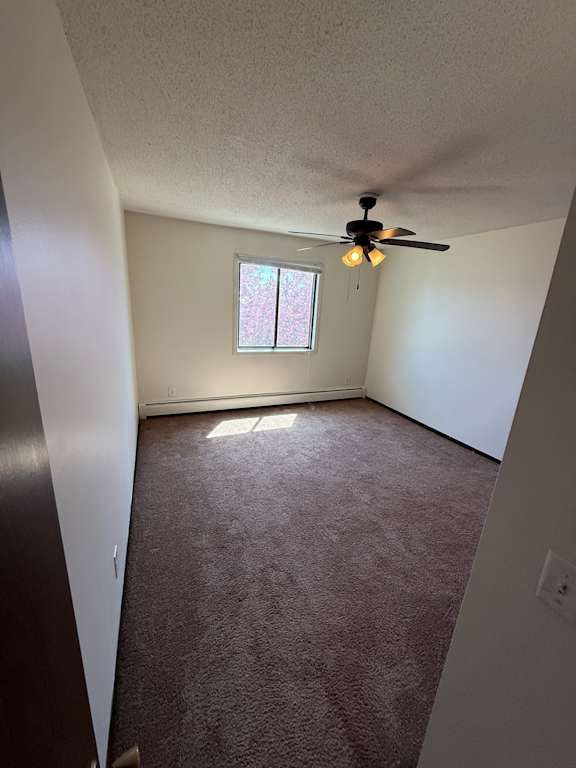 A ceiling fan hangs over a white ceiling in a room with a window.