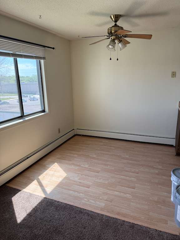 A ceiling fan with five blades is mounted on a white wall.