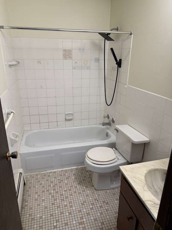 A white toilet is mounted on a wall with a shower stall behind it.