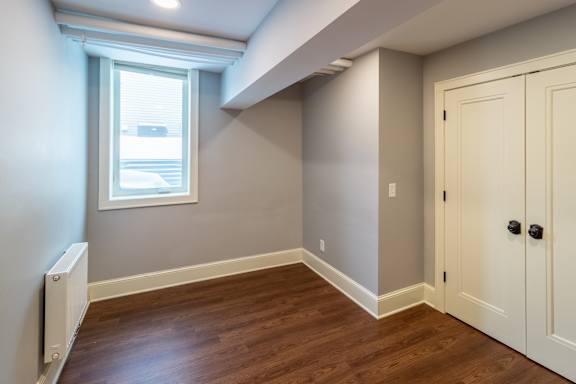 A room with a window and a wooden floor.