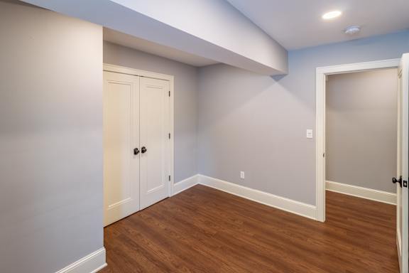 A room with a white door and a brown floor.