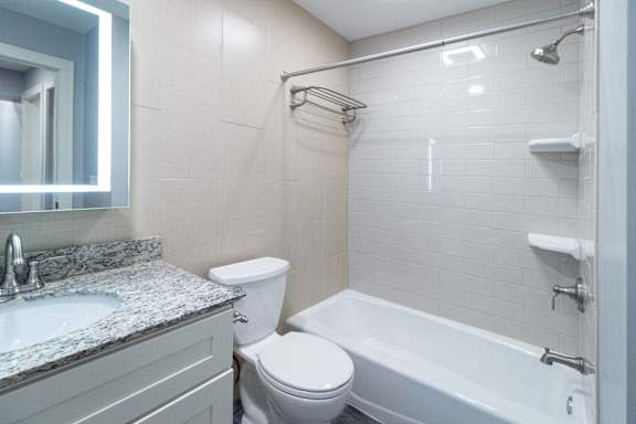 A white toilet sits next to a white bathtub in a bathroom.