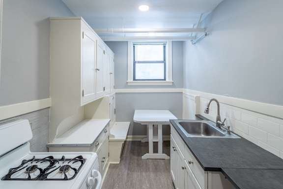 A small kitchen with a stove, sink, and a window.