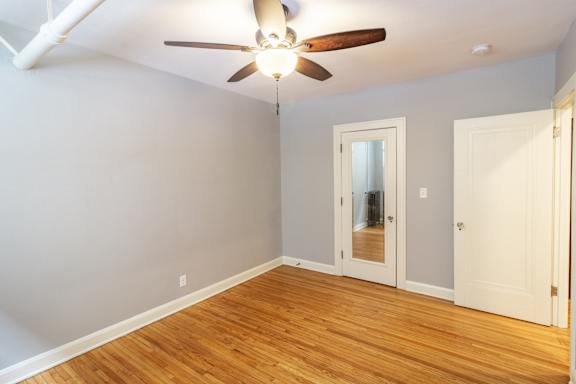 A room with a ceiling fan and wooden floors.