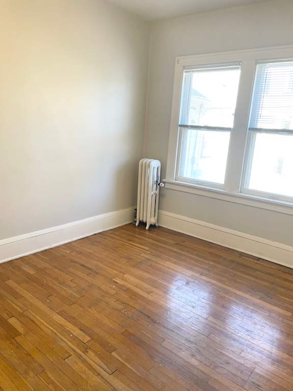 A room with a window and a radiator on the floor.