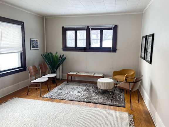 A living room with a rug, chairs, and a table.