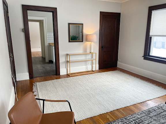 A room with a brown chair and a white rug.