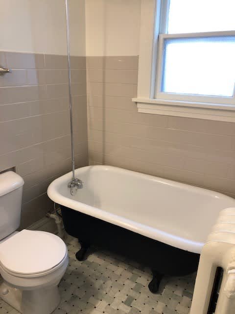 A white toilet sits next to a white bathtub in a bathroom.