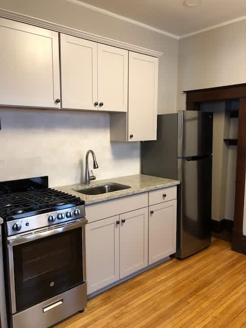 A kitchen with a stove, sink, and refrigerator.