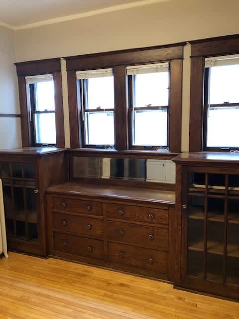 A brown wooden dresser with three windows on top.