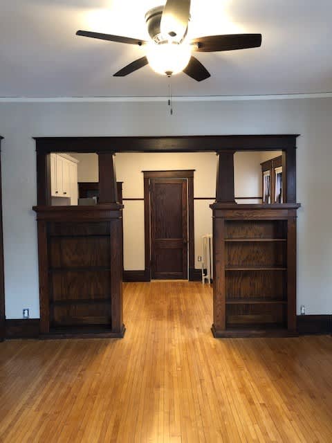 A room with a ceiling fan and wooden floors.