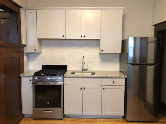 A kitchen with white cabinets and a stainless steel refrigerator.