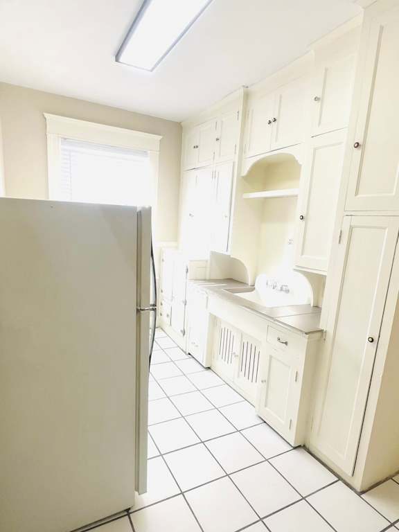 A white kitchen with a refrigerator and cabinets.