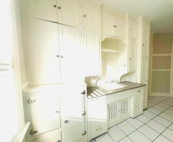 A kitchen with white cabinets and a black counter.
