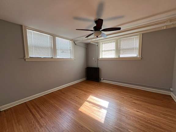 A room with a ceiling fan and wooden flooring.